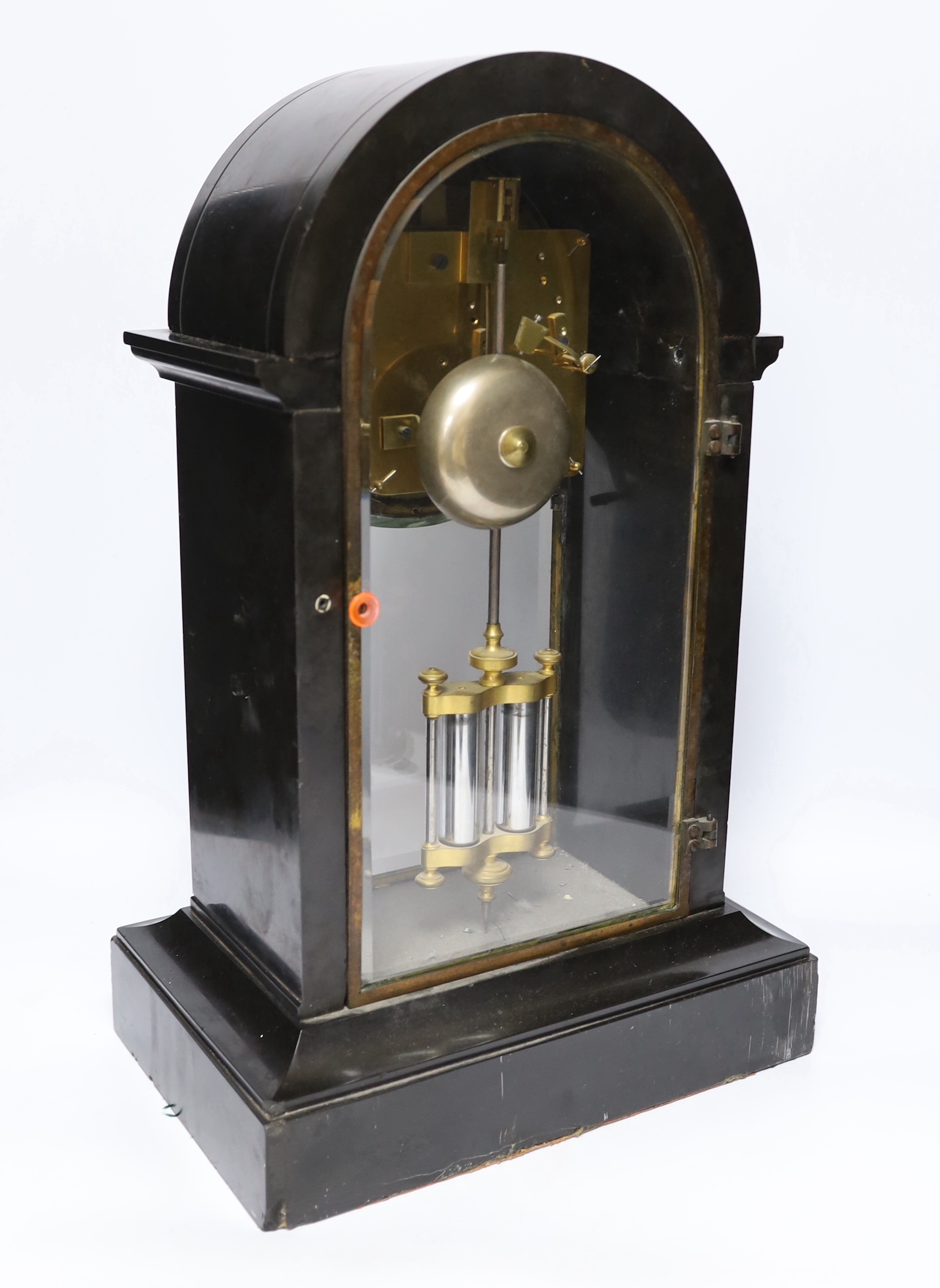 A slate cased domed mantle clock, with enamelled dial striking on a bell, with black Roman numerals above a bevelled glazed trunk with mercury style pendulum, 46cm